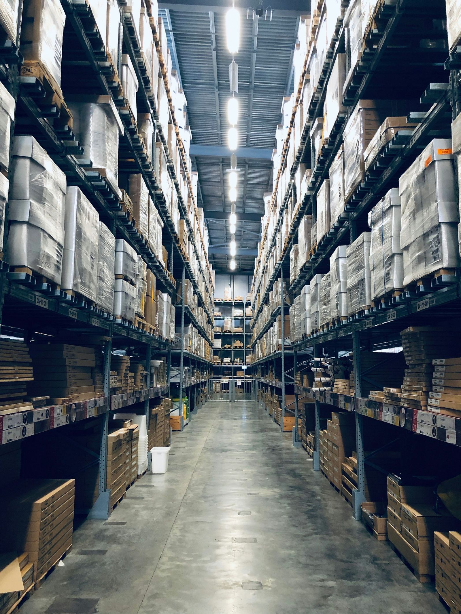 Tall pallet racking stocked with goods inside a large warehouse